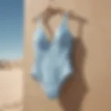 Elegant pale blue swimsuit hanging against a sandy backdrop